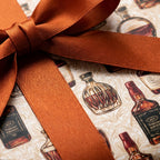 Vintage whiskey wrapping paper with a rust satin ribbon, luxury masculine gift wrap by Wrapped Studios.