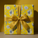 Luxury yellow floral wrapping paper with blue botanicals and a gold satin ribbon, by Wrapped Studios.