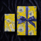 Yellow floral wrapping paper with blue botanical sketch pattern and satin ribbon, by Wrapped Studios.