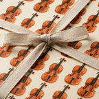 Watercolor violin wrapping paper tied with a natural linen bow, musical gift wrap by Wrapped Studios.
