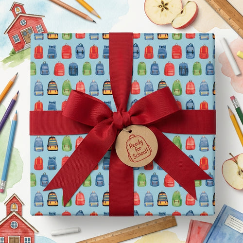 Watercolor back to school wrapping paper with colorful backpacks and a red ribbon bow by Wrapped Studios.