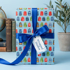 Back-to-school wrapping paper with watercolor backpacks and a blue satin bow, by Wrapped Studios.