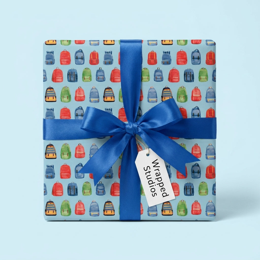 School backpack wrapping paper with a blue bow for kids birthday gifts, by Wrapped Studios.