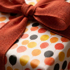 Balloon birthday wrapping paper with a rust orange linen bow by Wrapped Studios.