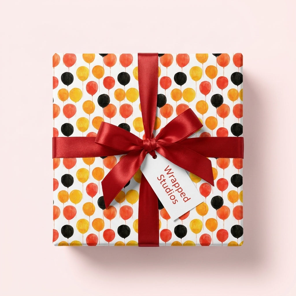 Playful balloon birthday wrapping paper with a red ribbon and gift tag by Wrapped Studios.