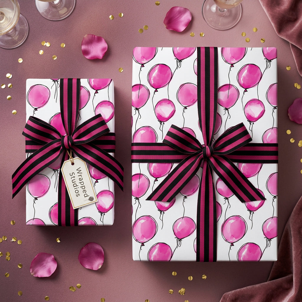 Wrapped Studios birthday wrapping paper: Two gifts wrapped in pink balloon pattern, tied with striped ribbon.
