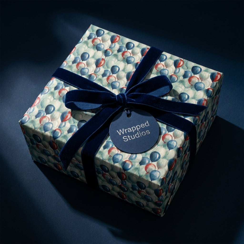 Luxury birthday wrapping paper with a blue balloon pattern and velvet bow by Wrapped Studios.