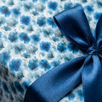 Luxury blue floral wrapping paper with a watercolor flower pattern and navy satin bow by Wrapped Studios.