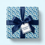 Blue floral wrapping paper with a navy satin bow on a luxury gift box by Wrapped Studios.