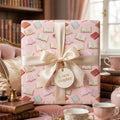 Pink book lovers wrapping paper with a luxury satin bow and gift tag by Wrapped Studios.