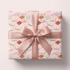Pink book pattern wrapping paper with satin ribbon bow by Wrapped Studios, aesthetic gift wrap for book lovers.