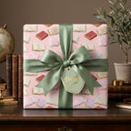 Pink bookish wrapping paper with a sage green ribbon and thank you tag by Wrapped Studios.
