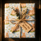 Blue floral bunny wrapping paper with a rustic twine bow and wooden tag, by Wrapped Studios.