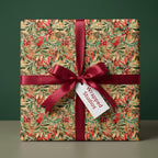 Elegant Christmas holly berry watercolor gift wrap with deep red satin ribbon. Wrapped Studios.