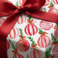 Pink watercolor ornament Christmas wrapping paper with a red satin bow by Wrapped Studios.