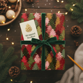 Christmas gift wrapped in festive tree print paper with a velvet green ribbon bow.