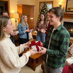 Friends exchanging holiday gifts in Christmas wrapping paper with red velvet bows by Wrapped Studios.