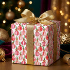 Watercolor pink ornament Christmas gift wrap with a gold bow by Wrapped Studios.