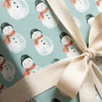 Snowman Christmas wrapping paper in sage green with a cream ribbon bow by Wrapped Studios.