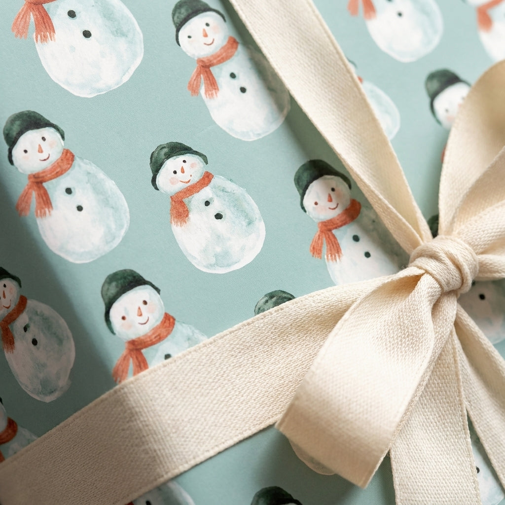 Snowman Christmas wrapping paper in sage green with a cream ribbon bow by Wrapped Studios.