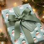 Cute snowman Christmas gift wrap with sage green ribbon and Happy Holidays tag by Wrapped Studios.