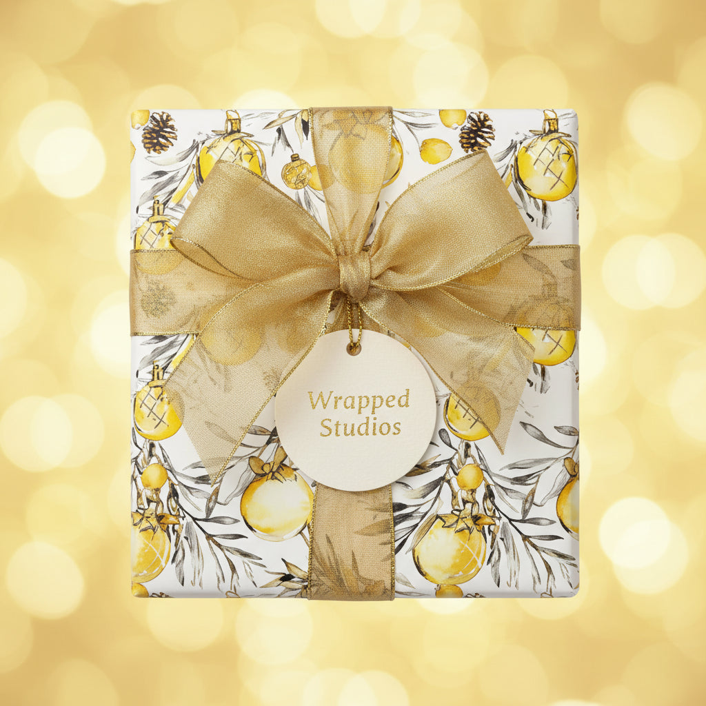 Square gift wrapped in Christmas wrapping paper with gold ornament design and gold ribbon.
