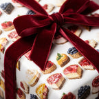 Cake slice themed birthday wrapping paper with a burgundy velvet ribbon bow.