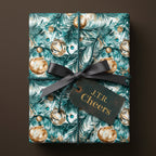 Elegant Christmas gift wrapped in teal and gold ornament paper with a dark gray ribbon from Wrapped Studios.