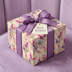 Elegant floral wrapping paper with a purple ribbon and "Best Wishes" tag from Wrapped Studios.