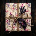 Elegant square gift wrapped in floral wrapping paper with twine and purple ribbon.
