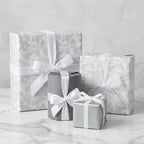 Luxury gray floral wrapping paper on wedding gift boxes with white ribbons by Wrapped Studios.
