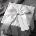 Luxury floral wrapping paper with a white satin bow and 'With Love' tag by Wrapped Studios.