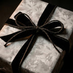 Moody vintage floral wrapping paper with a black velvet bow on a luxury gift box by Wrapped Studios.