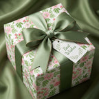 Elegant pink floral wrapping paper with a sage green satin bow on a wedding gift box by Wrapped Studios.