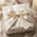 Luxury floral wrapping paper in elegant cream with an ivory satin bow and Wrapped Studios tag.