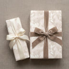 Elegant floral wrapping paper with velvet and satin bows on cream gift boxes by Wrapped Studios.