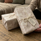 Elegant beige floral wrapping paper from Wrapped Studios on gift boxes tied with rustic twine.