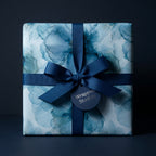 Luxury blue watercolor floral wrapping paper with a navy ribbon and tag from Wrapped Studios.