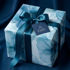 Luxury blue floral wrapping paper by Wrapped Studios on a gift box with a teal satin bow and tag.