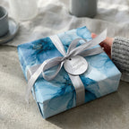 Luxury blue watercolor floral wrapping paper with a silver bow and tag by Wrapped Studios.