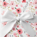 Elegant gift wrapped in pink floral wrapping paper with a white satin ribbon.