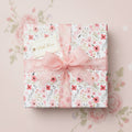 Square gift wrapped in floral wrapping paper with pink ribbon and bow, and a "With Love" tag.