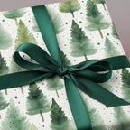 Elegant Christmas gift wrap with watercolor evergreen tree pattern and emerald green ribbon.