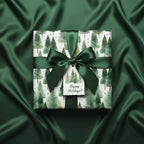 Elegant Christmas gift wrapped in forest green tree wrapping paper with matching satin ribbon.
