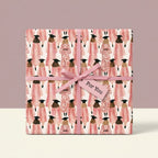 Pink graduation wrapping paper with illustrated female graduates and ribbon, by Wrapped Studios.