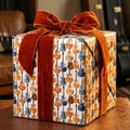 Vintage guitar wrapping paper by Wrapped Studios on a gift box tied with a burnt orange velvet bow.