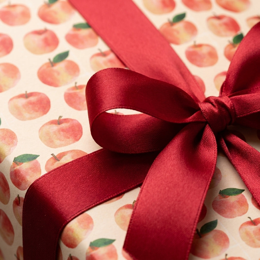 Watercolor apple wrapping paper tied with a luxury red satin ribbon bow by Wrapped Studios.