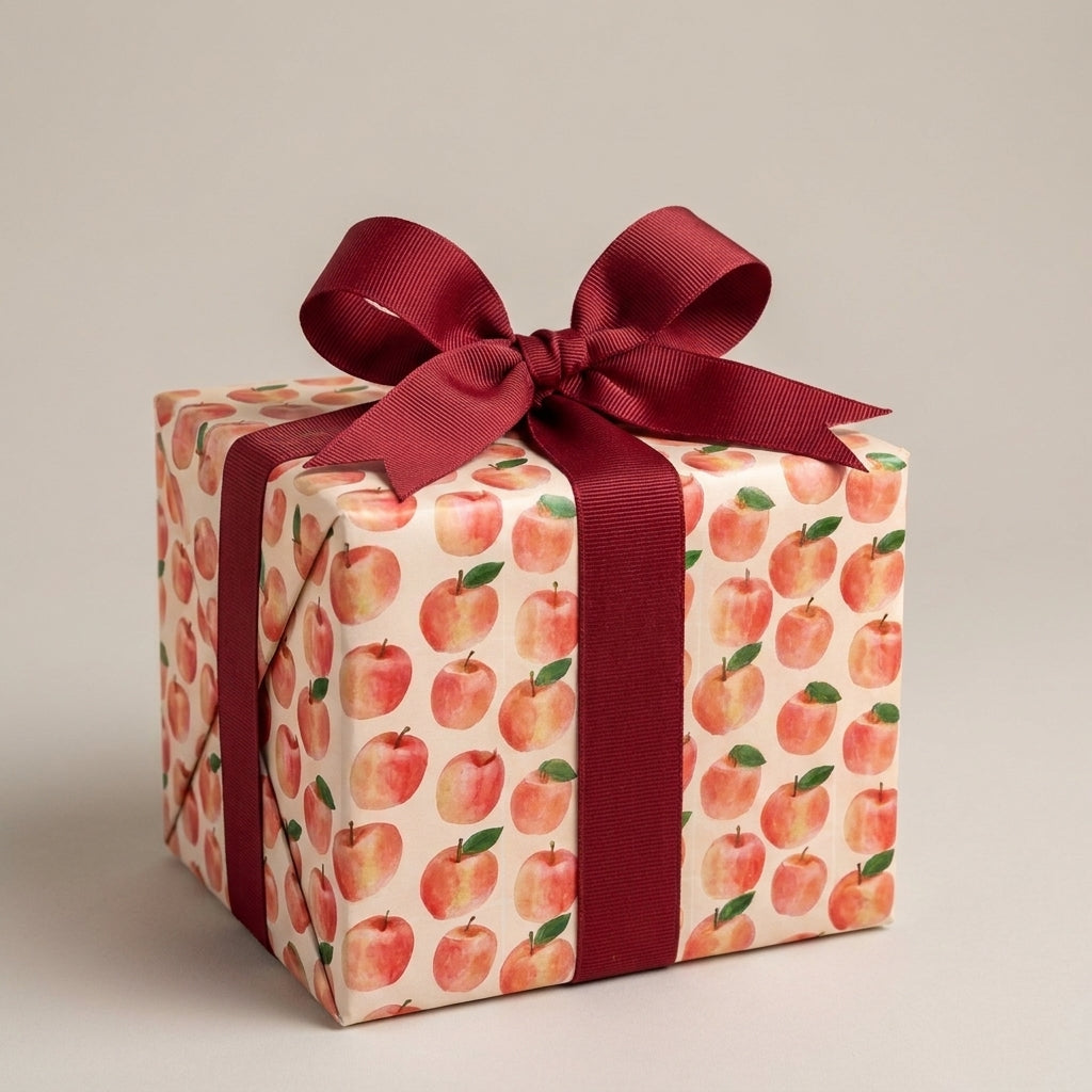 Watercolor apple wrapping paper on a gift box with a burgundy ribbon, by Wrapped Studios.