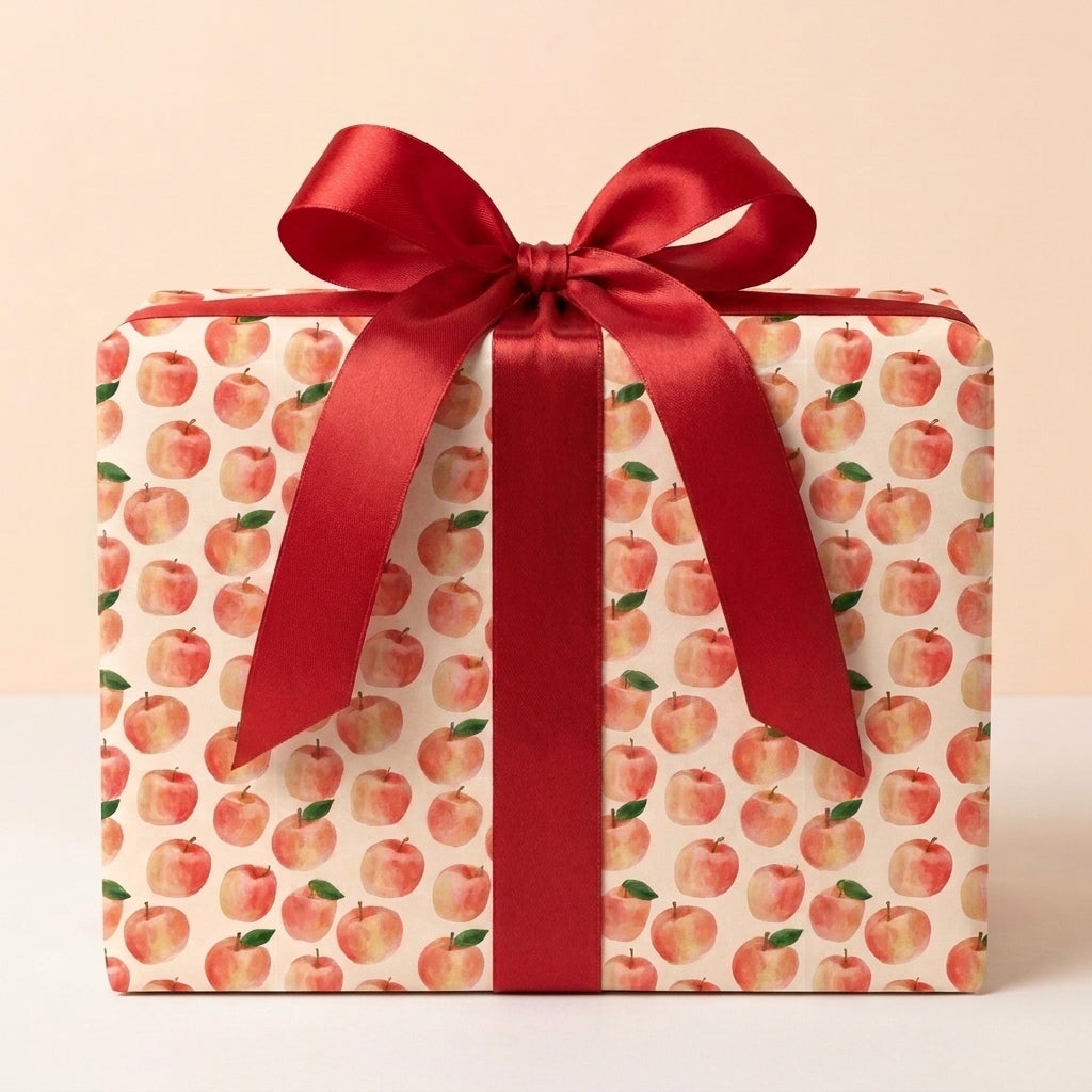 Watercolor apple wrapping paper with a red satin ribbon on a gift box by Wrapped Studios.