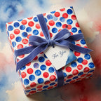 Red and blue watercolor polka dot wrapping paper with a velvet bow by Wrapped Studios.